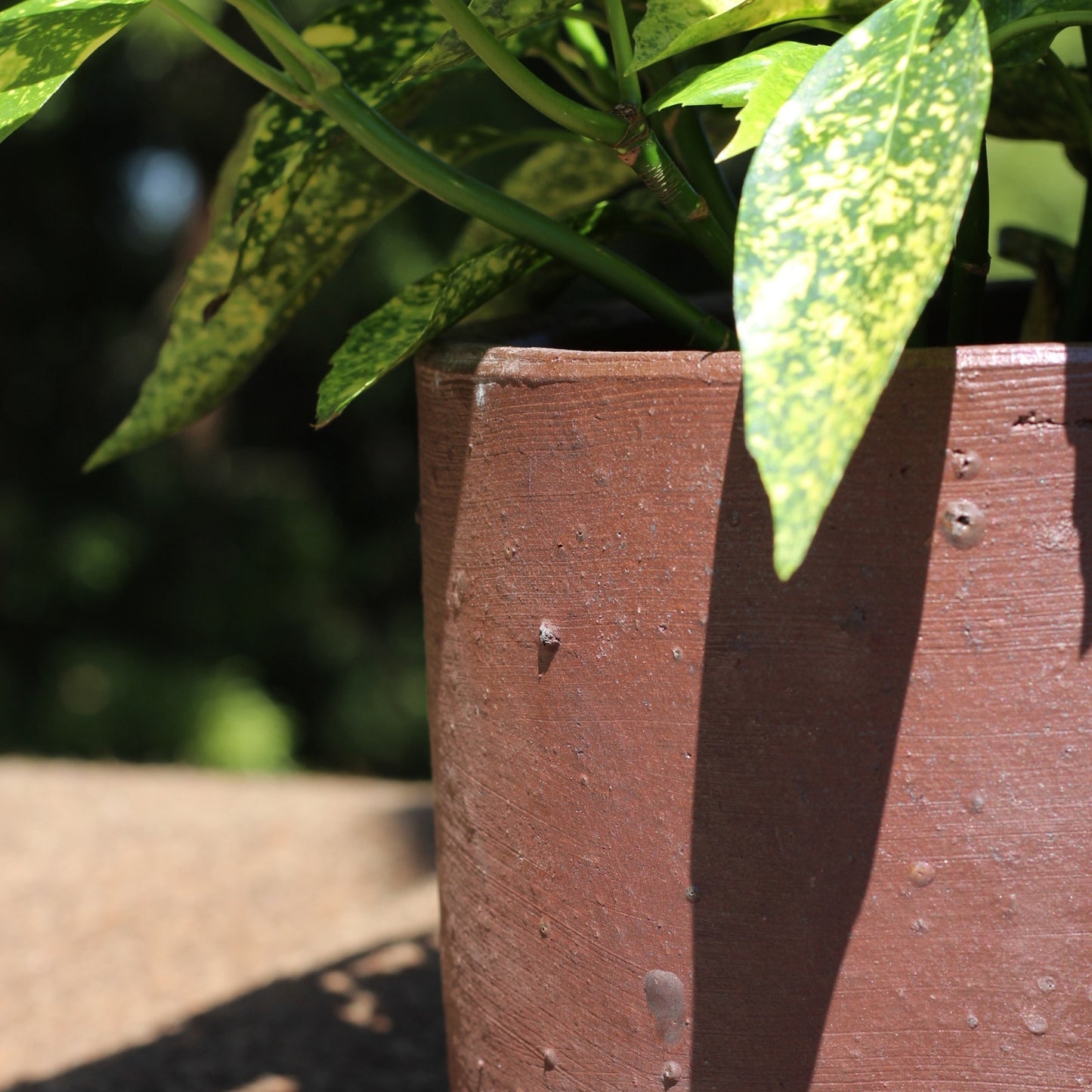 Close-up do acabamento do vaso cilíndrico de gres, com textura artesanal e tom cru elegante para interiores e exteriores
